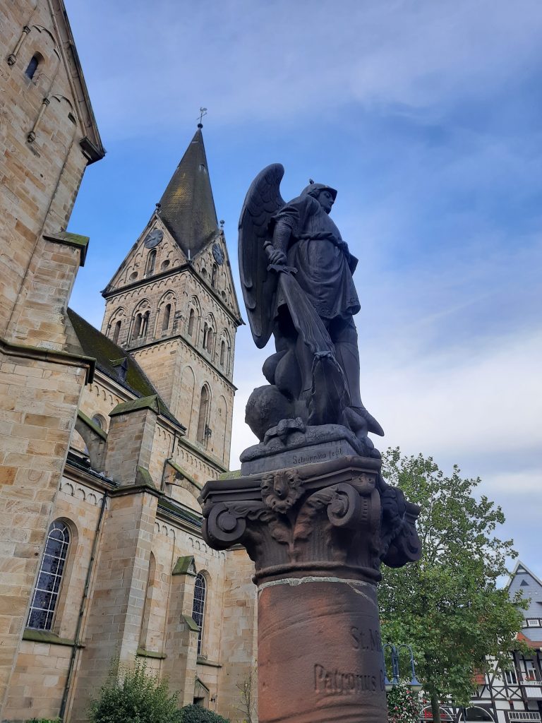 Blick auf den St. Michaelsbrunnen vor der St.Agatha Kirche in Mettingen aus der Perspektive des Tüötten Houk Mettingen